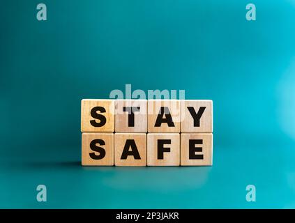 Das Konzept „sicher bleiben“. Wort „Stay Safe“ auf Holzwürfelblock isoliert auf blauem Hintergrund, minimalistischer Stil. Bleiben Sie zu Hause, Social-Media-Kampagne für Stockfoto