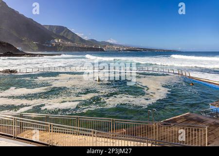 Meerwasser-Swimmingpool in Punta del Hidalgo auf Teneriffa mit der Küstenstadt Bajamar und dem Berg Teide im Hintergrund. Stockfoto