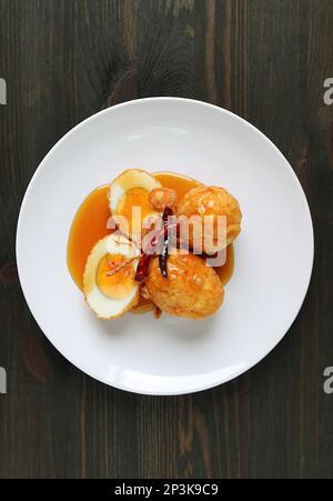 Ein Teller thailändischer berühmter hausgemachter Gerichte, Kai Look Keuy oder Son in Law Eggs auf Holzhintergrund Stockfoto