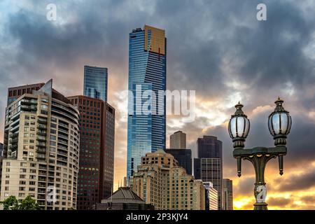 Die Sonne geht über Melbourne unter. Eine altmodische Laterne im Vordergrund mit einem modernen Stadtbild im Hintergrund. Stockfoto
