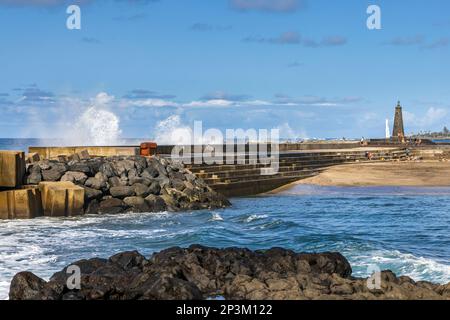 Wellen stürzen in das Wellenbrecherwasser und schützen den Sandstrand von Bajamar auf Teneriffa, Kanarische Inseln. Stockfoto