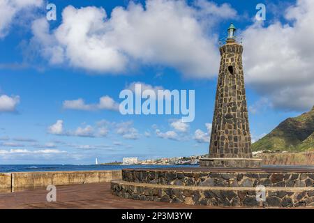 Leuchtturm im Ferienort Bajamar mit dem Dorf Punta del Hidalgo im Hintergrund. Gemeinde San Cristobal de La Laguna, Teneriffa. Stockfoto