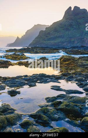 Die zerklüftete Küste von Punta del Hidalgo bei Sonnenaufgang. Mit den Anaga-Bergen im Hintergrund, Teneriffa, Kanarische Inseln Stockfoto