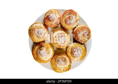 Buns Choux Gebäck, isoliert auf weißem Hintergrund. Kuchen mit Puderzucker bestreut. Scones mit Pudding auf einem Teller, Draufsicht Stockfoto