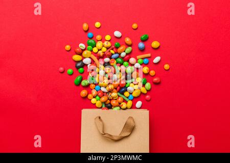 Einkaufspapier Geschenktasche in der Ecke mit verschiedenen traditionellen Süßigkeiten, die auf farbigen Hintergrund fallen, mit Kopierbereich. Frohes Weihnachtsangebot. Stockfoto