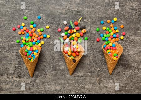 Waffelkonus voller traditioneller Süßigkeiten, die auf farbigen Hintergrund fallen, mit Platz für Kopien. Frohes Weihnachtsangebot. Stockfoto