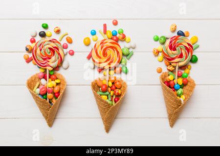 Waffelkonus voller traditioneller Süßigkeiten, die auf farbigen Hintergrund fallen, mit Platz für Kopien. Frohes Weihnachtsangebot. Stockfoto