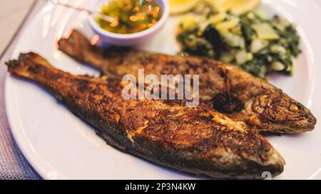 Gebratene gegrillte Forellen, gebratener Pastackfisch auf Teller mit Spinat und Kartoffelpüree, serviert in einem traditionellen Meeresfrüchtestaurant in Montenegro, S. Stockfoto