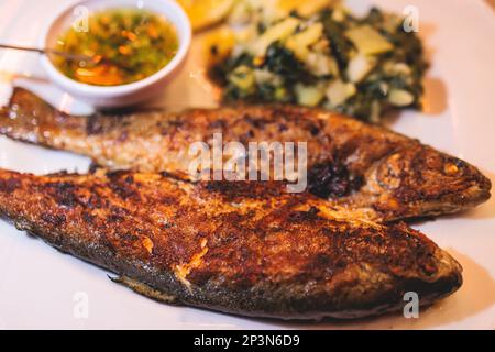 Gebratene gegrillte Forellen, gebratener Pastackfisch auf Teller mit Spinat und Kartoffelpüree, serviert in einem traditionellen Meeresfrüchtestaurant in Montenegro, S. Stockfoto