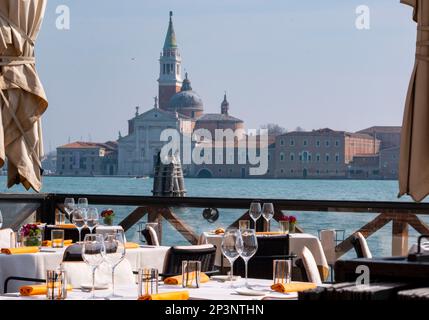 Restaurant im Freien am Ufer des Canale della Giudecca mit Blick auf die Isola di San Giorgio Maggiore, Venedig, Italien. Stockfoto