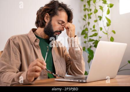 Gestresster müder Geschäftsmann mit Kopfschmerzen vor dem Computer. Stockfoto
