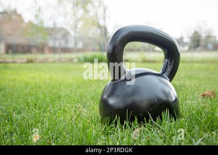 schweres Eisen schwarz Kettlebell auf dem grünen Rasen in Hinterhof - outdoor-Fitness-Konzept Stockfoto