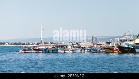 Nesebar, Bulgarien - 21. Juli 2014: Vergnügungsboote liegen in der Nähe des Wellenbrechers mit kreuzförmigem Leuchtturm vor. Gewöhnliche Menschen laufen an der Küste Stockfoto