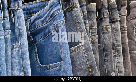 Viele Jeans, die an der Spielbank hängen. Eine Reihe Hosen Jeans, die im Schrank hängen, Konzept des Kaufs, Verkaufs, Einkaufs und Jeans Mode Stockfoto