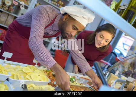 Ladenbesitzer gibt Frau Gebäck Stockfoto