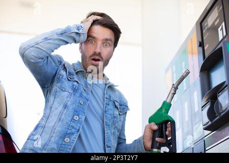 Ein emotionaler Geschäftsmann, der Geld mit Benzin fürs Auto zählt Stockfoto