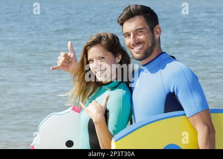 Ein Surfpaar, das shaka-Handzeichen macht Stockfoto