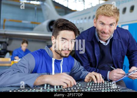 Zwei Mechaniker arbeiten auf ein kleines Flugzeug im Hangar Stockfoto