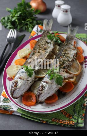 Meerbarbe gebacken mit Gemüse, Gewürzen und Zitrone serviert auf einem Teller, Stockfoto