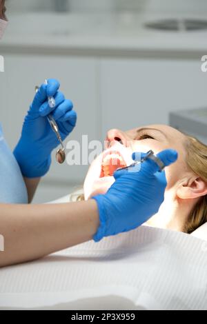 Zahnarztinjektion am Zahnfleisch der Patientin in der Klinik. Ein Arzt in blauen Handschuhen mit einer Spritze in den Händen gibt dem Patienten mit offenem Mund eine Anästhesieinjektion Hochwertiges Foto Stockfoto