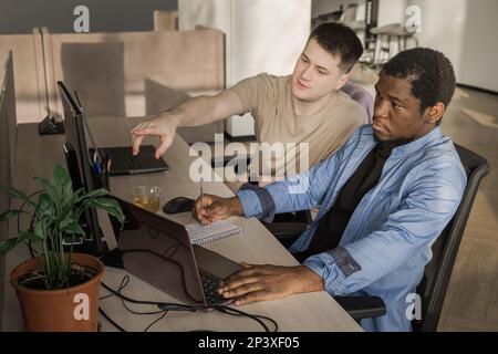 Zwei Programmierer, die im Büro eines Softwareentwicklungsunternehmens arbeiten. Codierungstechnologien, Baustellendesign. Erfolgreiche vielfältige Teamarbeit. Cyberspace Stockfoto