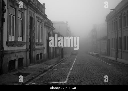 Eine Straße am Morgen im dichten Nebel. Porto, Portugal. Schwarzweißfoto. Stockfoto