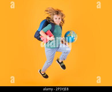 Die ganze Länge des aufgeregten Kindersprungs. Zurück in die Schule. Schulkind in Schuluniform mit Rucksack und Kugelsprung. Schulkinder, die auf das Studio springen Stockfoto