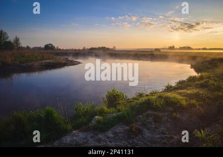 Wunderschöne neblige Landschaft am Morgen. Sonnenaufgang über dem Fluss in Ponidzie in Polen. Stockfoto