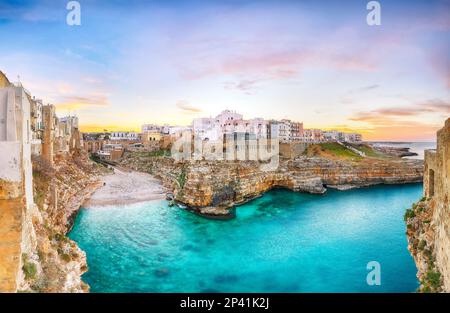 Atemberaubender Sonnenuntergang am Golf von Cala Paura mit Bastione di Santo Stefano und Lama Monachile Beach im Hintergrund. Polignano a Mare, Apulien, Italien, Provinz Stockfoto