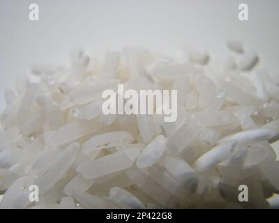 Makroaufnahme der Details eines kleinen Stapels weißen Reises vor weißem Hintergrund. Stockfoto