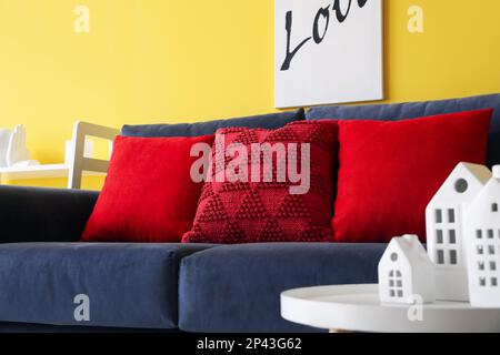Rote Kissen auf blauem Sofa im Wohnzimmer, Schließfach Stockfoto