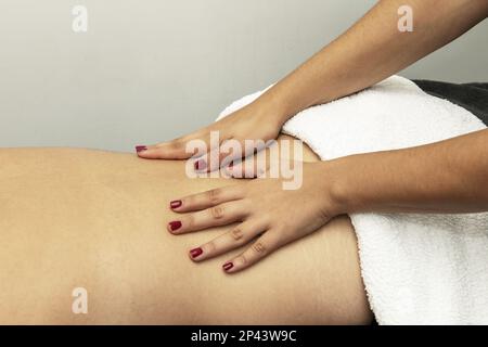 Hände einer Masseurin auf dem Rücken eines Patienten, der eine therapeutische Massage anwendet Stockfoto