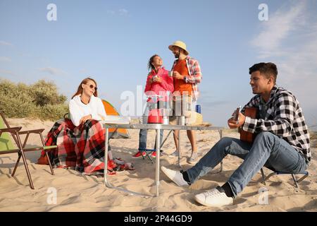 Freunde, die sich an der Sandküste ausruhen. Camping am Strand Stockfoto