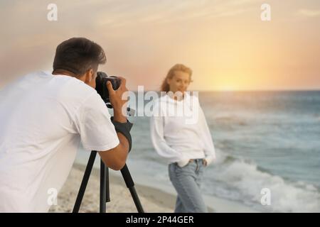 Fotograf fotografiert Modell mit professioneller Kamera in der Nähe des Meeres Stockfoto