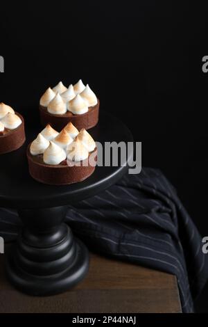 Köstliche gesalzene Karamellschokoladentörtchen auf einem Holztisch vor dunklem Hintergrund Stockfoto