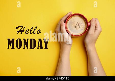 Hallo Montag, beginnen Sie Ihre Woche mit guter Laune. Frau mit einer Tasse Kaffee auf gelbem Hintergrund, Draufsicht Stockfoto