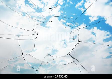 Blick durch ein kaputtes Fenster am bewölkten Himmel Stockfoto