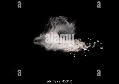 Spliss von Steinrückständen, die mit weißem Staub auf schwarzem Hintergrund explodieren. Stockfoto