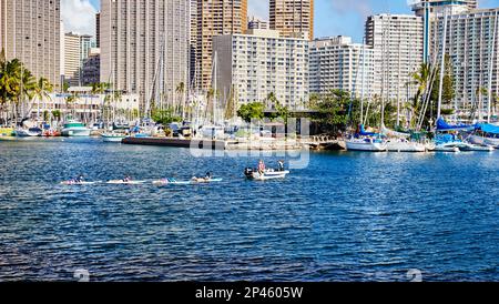 Honolu, Oahu, Hawaii, USA, - 6. Februar, 2023 Uhr: Menschen auf Surfbrettern, die von einem kleinen Motorboot im Hafen von Ilikai gezogen werden Stockfoto