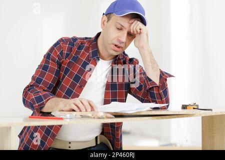 frustriert Mann Anleitung lesen und Zusammenstellung Selbstmontage Möbel Stockfoto