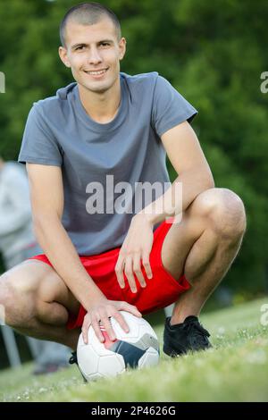 Ein junger Fußballspieler, der auf dem Rasen knien will Stockfoto
