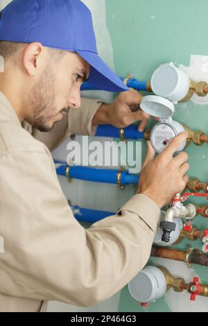 Junger männlicher Unternehmer liest Wasserzähler ab Stockfoto