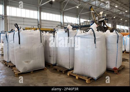 Riesige Plastiktüten mit Produkten auf Paletten in der Recyclingfabrik Stockfoto