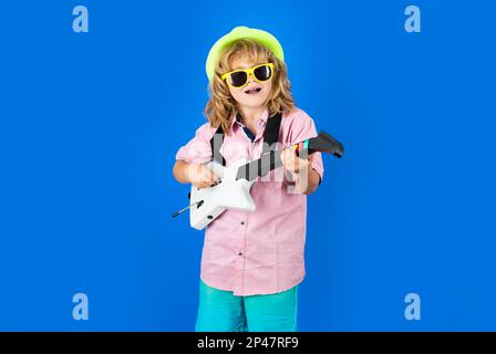 Der süße Junge singt und spielt mit hellen Emotionen auf der E-Gitarre. Ein Fashion-amerikanischer Country-Boy spielt Musik. Stockfoto