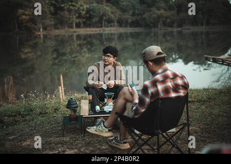 Junger zwei-Mann, der am freien Campingtag Kaffee trinkt Stockfoto