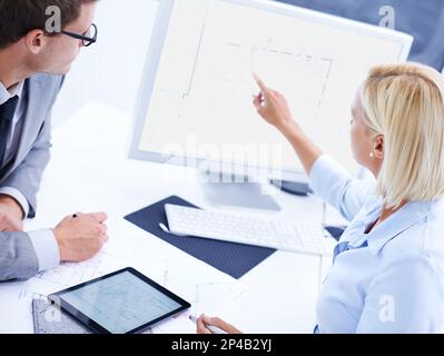 Fokus auf Qualität und Genauigkeit. Ein Architekt, der einem Kollegen etwas auf einem Computer zeigt. Stockfoto