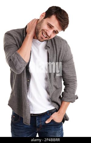 Stress kann eine Nervensäge sein. Studiofoto eines jungen Mannes, der vor Schmerzen grimmt, während er seinen Hals hält. Stockfoto