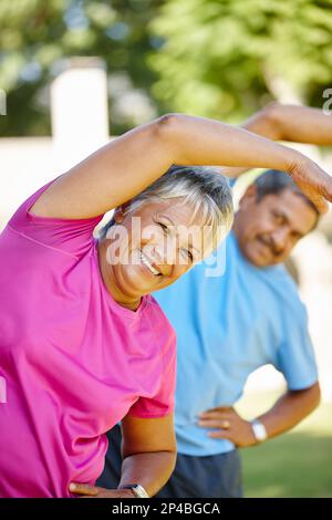 Fit bleiben und Spaß miteinander haben. Porträt eines erwachsenen Ehepaars, das zusammen im Garten trainiert. Stockfoto