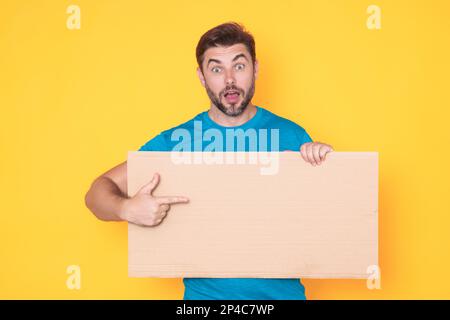 Der Mann hält ein Schild, eine leere Karte. Plakat für Ihr Produkt bereit. Unterschreib in deine SMS. Ein Mann zeigt leere Schilder über dem isolierten Studio-Hintergrund und zeigt auf ihn Stockfoto