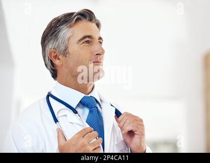 Die Bestrebungen, der beste Arzt zu sein, den es gibt. Ein gut aussehender, reifer Arzt, der aufmerksam im Krankenhaus stand. Stockfoto